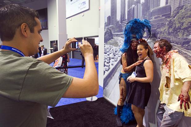 Danielle Stevenson, a senior systems training specialist with Konami Gaming, poses with zombies during the G2E convention at the Sands Expo Center Tuesday, Sept. 24, 2013. The zombies were promoting a new "Walking Dead" video slot machine by Aristocrat. The slots are themed after AMC's Walking Dead television drama.