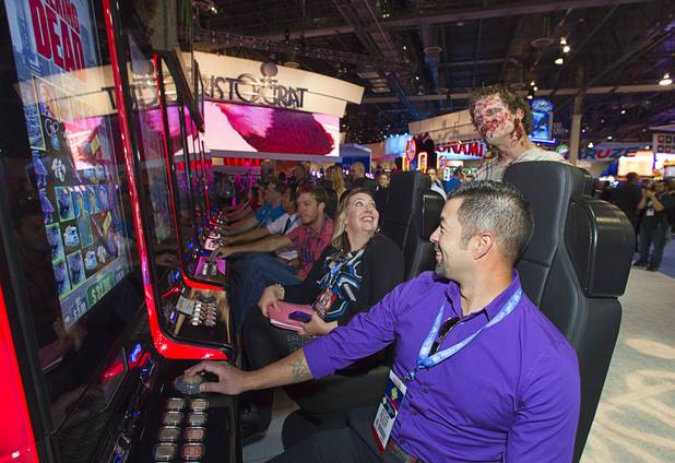 A zombie looks on as people try out the new "Walking Dead" video slot machine by Aristocrat during the G2E convention at the Sands Expo Center Tuesday, Sept. 24, 2013. The slots are themed after AMC's Walking Dead television drama.