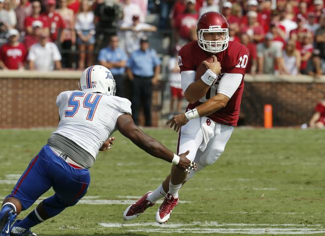 Oklahoma quarterback Blake Bell (10) avoids a tackle by Tulsa defender Derrick Alexander Jr. (54) in the first quarter of an NCAA college football game in Norman, Okla., Saturday, Sept. 14, 2013. 