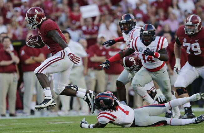 Alabama running back T.J. Yeldon (4) runs for yardage as Mississippi defensive back Trae Elston (7) defends during the first half of an NCAA college football game against Mississippi in Tuscaloosa, Ala., Saturday, Sept. 28, 2013.