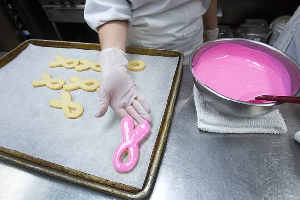Pastry chef Katie Ward frosts ribbon-shaped cookies at the Red Rock Resort bakery Tuesday, Oct. 1, 2013. Station Casinos is hosting its fourth annual "Project Pink" initiative for National Breast Cancer Awareness Month. Throughout October, the majority of station properties will donate a portion of its proceeds from Project Pink retail sales and Pink gaming winnings to the Southern Nevada affiliate of Susan G. Komen, an organization supporting breast cancer research.