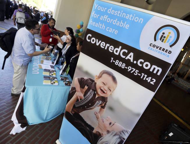 An information table is busy at Union Station in downtown Los Angeles as people seek information on state-provided health insurance, while a celebration is underway to inaugurate the first day people can enroll, Tuesday, Oct. 1, 2013.