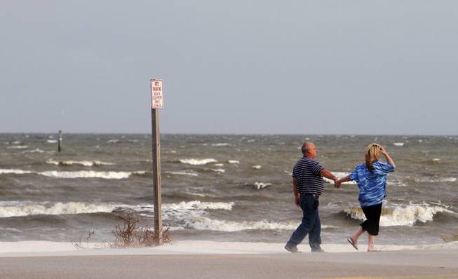 A couple walks along the beach on Thursday, Oct. 3, 2013, in Gulfport, Miss. Preparations are underway along the Mississippi Gulf Coast as Tropical Storm Karen moves through the Gulf of Mexico.