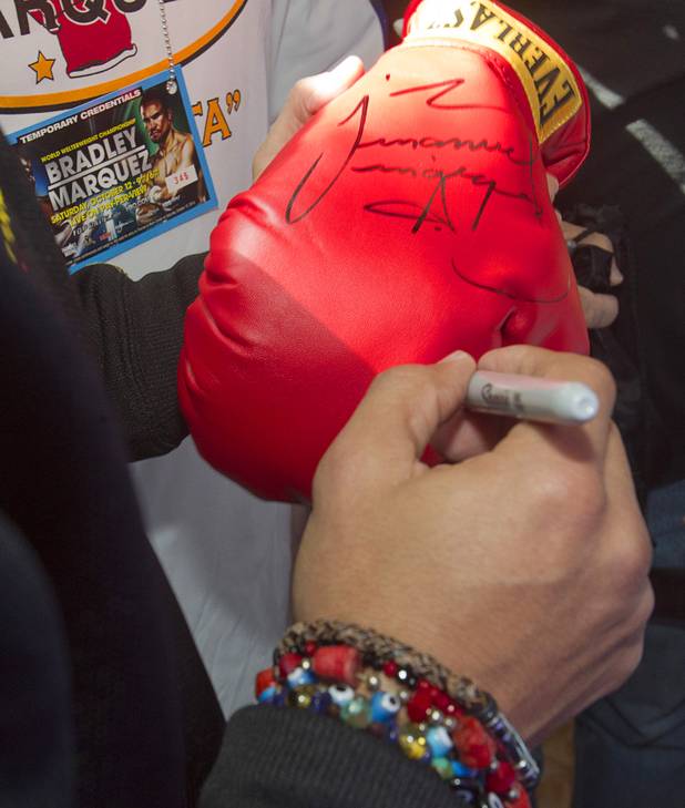 Mexican boxer Juan Manuel Marquez signs a boxing glove for a fan as he arrives at the Wynn Las Vegas Resort Tuesday, Oct. 8, 2013. Marquez will challenge undefeated WBO welterweight champion Timothy Bradley Jr. at the Thomas & Mack Center Saturday.