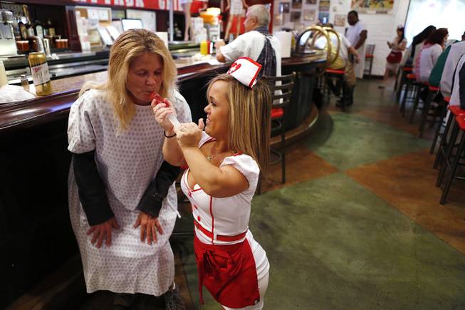 Lisa Krahn, left, of Canada, gets fed a jello shot by waitress Lorren Cackowski at the Heart Attack Grill in downtown Las Vegas on Tuesday, October 8, 2013.