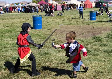 Brothers Jackson Reeves, 7, and Maddox Reeves, 3, battle near a food area during the Age of Chivalry Renaissance Festival in Silver Bowl Park on Sunday, Oct. 9, 2011.
