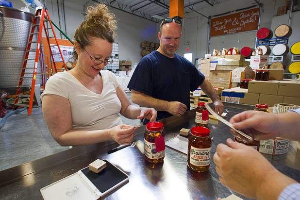 Angel Brubaker and her husband Garett put labels on mason jars of moonshine during tastings at the Las Vegas Distillery in Henderson Saturday, Oct. 12, 2013. The distillery unveiled their newest spirit called Grandma's Apple Pie Moonshine. The distillery will feature additional tastings on Oct. 19 and 26.