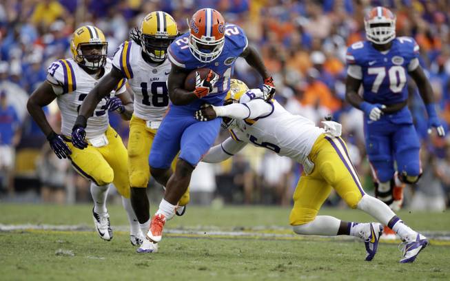 Florida running back Kelvin Taylor (21) carries as  safety Craig Loston (6) tries to tackle with linebacker Lamin Barrow (18) and linebacker Lamar Louis (23) pursuing in the second half of an NCAA college football game in Baton Rouge, La., Saturday, Oct. 12, 2013.  LSU won 17-6. 