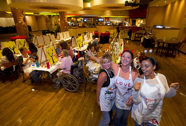 "Chief Bee Officer" Teresa Leming, left, "BeeExtraordinaire" Caroline App, center and "Beekeeper" Jordan Turner dance during a class at the Buzz'N Brushes art studio in the Orleans Sunday, Oct. 13, 2013.  The studio combines art and entertainment for beginners and shares space with a bar and pizza kitchen.