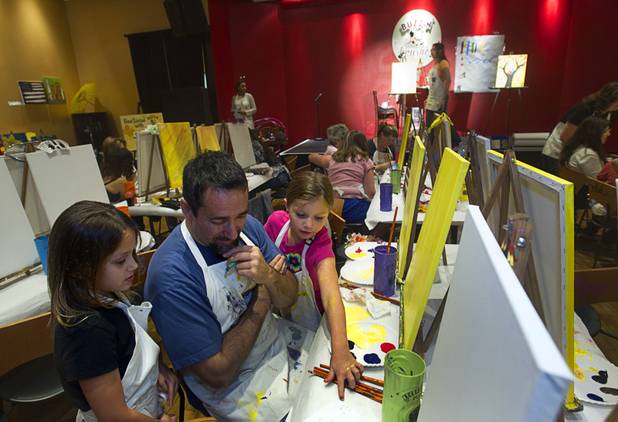 Chris Berry and his daughters Julia, left, 6, and Anna, 9, work on a trivia game during a class at the Buzz'N Brushes art studio in the Orleans Sunday, Oct. 13, 2013.  The studio combines art and entertainment for beginners and shares space with a bar and pizza kitchen.