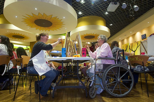 Brianna Allison, left, and Janice Zickafoose work on paintings during a class at the Buzz'N Brushes art studio in the Orleans Sunday, Oct. 13, 2013.  The studio combines art and entertainment for beginners and shares space with a bar and pizza kitchen.