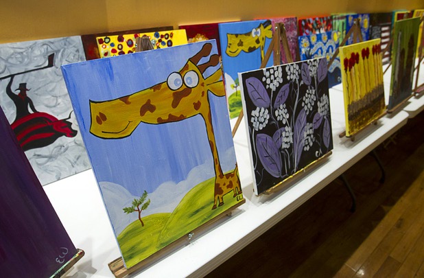 Paintings are displayed at the Buzz'N Brushes art studio in the Orleans Sunday, Oct. 13, 2013.  The studio combines art and entertainment for beginners and shares space with a bar and pizza kitchen. 