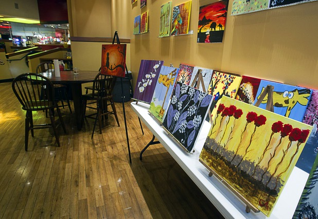 Paintings are displayed at the Buzz'N Brushes art studio in the Orleans Sunday, Oct. 13, 2013.  The studio combines art and entertainment for beginners and shares space with a bar and pizza kitchen. 