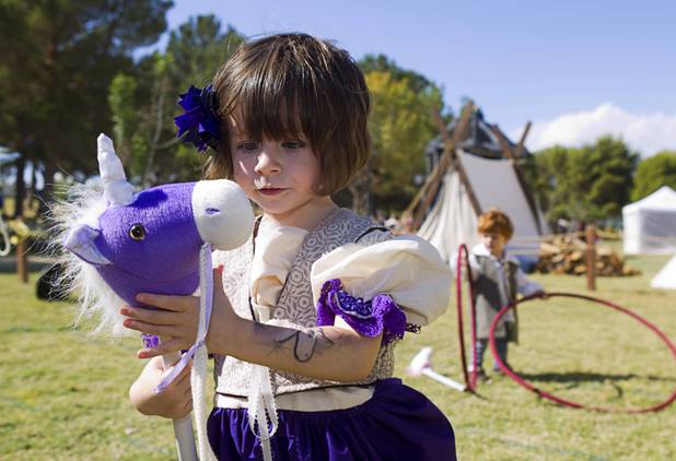 Elle Tripp, 3, plays with a toy horse at the Kingdom of Coreathea during the Age of Chivalry Renaissance Festival at Sunset Park Sunday, Oct. 13, 2013.