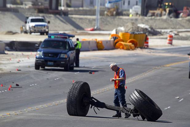 An inspector looks at the front axle of a cement truck at the scene of a fatal crash on the northern 215 beltway near Jones Boulevard Tuesday, Oct. 15, 2013. The accident has closed the beltway in both directions between Jones Boulevard and Sky Pointe Drive.