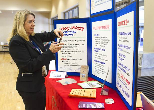 North Las Vegas Police Department victim advocate Jan Lucherini takes a photo of the Nevada Adult Day Healthcare Center display during a senior safety fair at the East Las Vegas Community Center, 250 North Eastern Ave., Tuesday, Oct. 15, 2013.