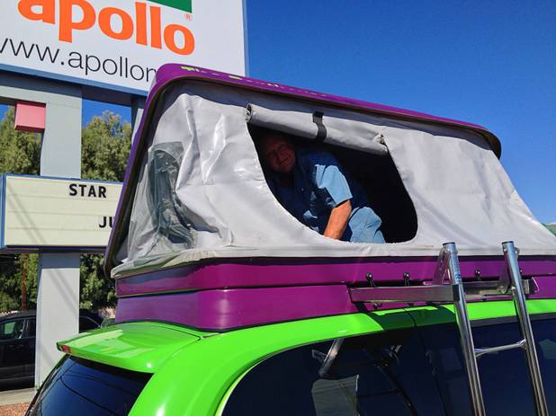 Kurt Luthy opens windows on the double bed atop the van.