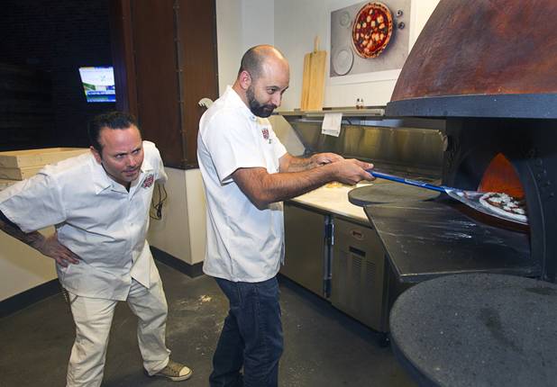 Tony Gemignani, left,  watches as Las Vegas Weekly food editor Brock Radke places a a margherita pizza into a wood-fired oven at the new Pizza Rock restaurant at Third Street and Ogden Avenue in downtown Las Vegas Thursday, Oct. 17 2013.