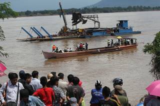 Onlookers watch the search operation for the lost Lao Airlines plane on the banks of the Mekong River in Pakse, Laos, Thursday, Oct. 17, 2013. Rescuers in fishing boats pulled bodies from the muddy river as officials in Laos ruled out finding survivors from a plane that crashed in stormy weather, killing 49 people from 11 countries. A debris field on the riverbank suggests the boats are very close to where the ill-fated flight must have hit the water.