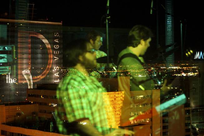 Local band Moksha is reflected off the rooftop glass wall during their set at the "Rooftop Fall Ball 3" at Binion's Gambling Hall & Hotel pool deck, Friday, Oct. 18, 2013.