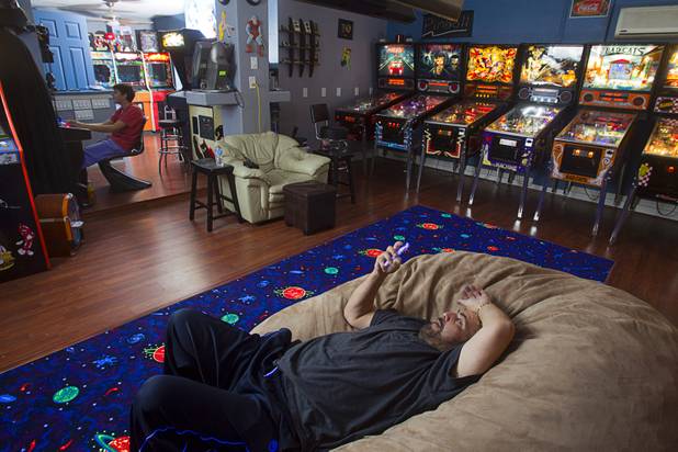 Pinball repairman Craig Snelling relaxes in the game room as his son Shane, 15, plays a video game Tuesday, Oct. 22, 2013. Snelling is a pinball machine repairman and owner of Billiards 'N More, a billiards and game room supply store.