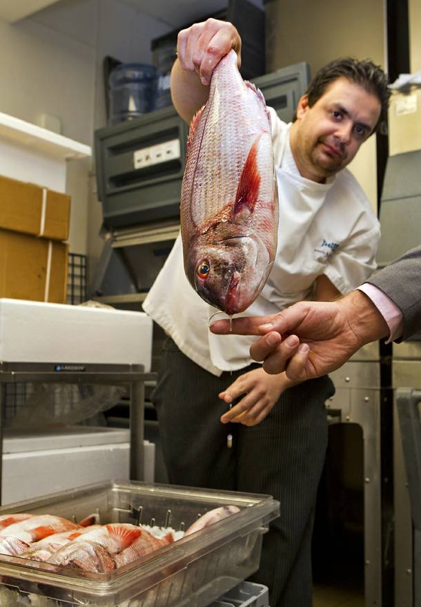 Milos chef Nikos Georgousis is amused by the hook still in the mouth of a lithrini he unwraps Wednesday Oct. 23, 2013.