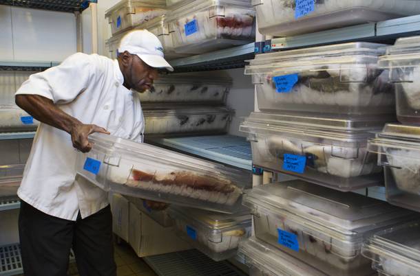 Fish preparer Morison Becton ices and stores the fresh catch at Milos, where customers will view the seafood and select a meal, Wednesday Oct. 23, 2013.