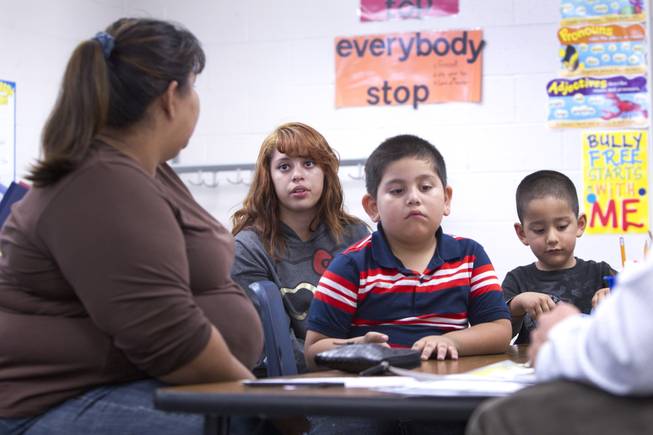 Melynda Espinoza, 15, interprets for her mother during a parent-teacher conference for her brother Miguel, center, at Lois Craig Elementary School in North Las Vegas Wednesday, Oct. 23, 2013. Another brother Christopher, 3, is at right. About 80 percent of students at the school are Hispanic.