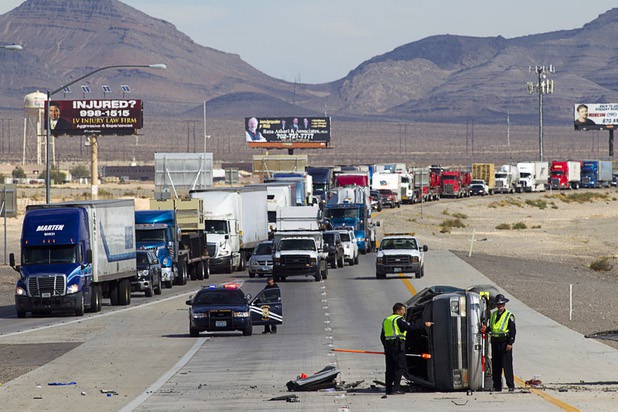 Nevada Highway Patrol troopers take measurements at the scene of a rollover accident in the southbound lanes of I-15 near Lamb Boulevard on Wednesday, Oct. 23, 2013. The van was northbound but, possibly due to tire failure, crossed the median and rolled.