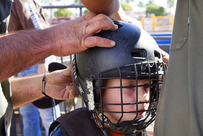 Vance Rupp, 7, of Polk City, Iowa gets fitted for a helmet before a Mutton Bustin' competition at the Tyson Fan Zone & Marketplace at Mandalay Bay Thursday, Oct. 24, 2013. Riders must be four to seven years old and weigh 60 lbs. or less. The event was part of the the 2013 Professional Bull Riders Built Ford Tough World Finals. Rupp won the morning competition.