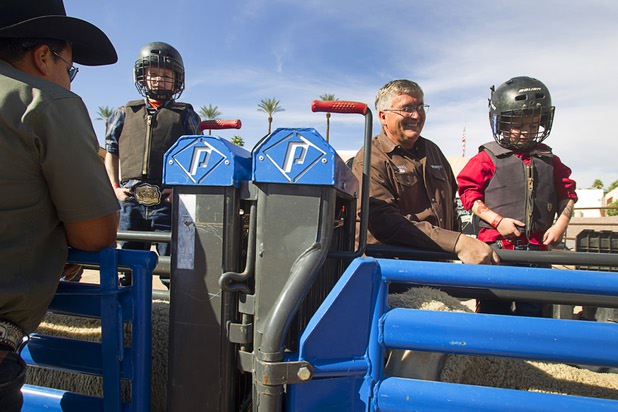 Vance Rupp, left, 7, and his brother AJ, 4, prepare for  a Mutton Bustin' competition at the Tyson Fan Zone & Marketplace at Mandalay Bay Thursday, Oct. 24, 2013. Their grandfather Rob Johansen stands by AJ. The event was part of the the 2013 Professional Bull Riders Built Ford Tough World Finals.