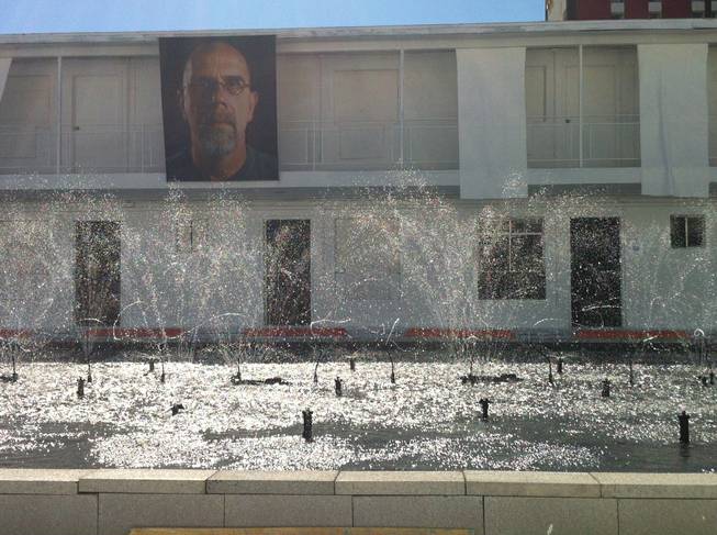 Artist Eric Tillinghast's “Sump Lux Fountain,” a 30-by-60-foot reservoir in the courtyard of the Town Lodge Motel, shoots water with a Chuck Close tapestry in the background Saturday, Oct. 26, 2013.