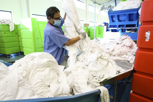 An employee looks for secretly hidden ink packets while sorting linens at Apex Linen in Las Vegas Tuesday, October 30, 2013.