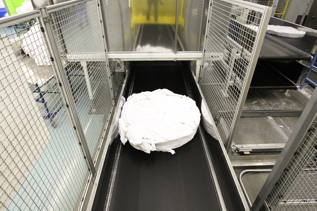 A load of freshly washed sheets travels along a conveyer belt during a walk-through of Apex Linen in Las Vegas Tuesday, October 30, 2013.