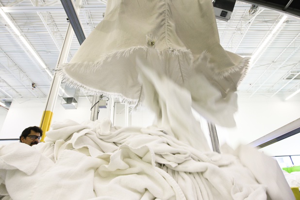 Soft and bright white towels fall from a dryer shoot during a walk-through of Apex Linen in Las Vegas Tuesday, October 30, 2013.