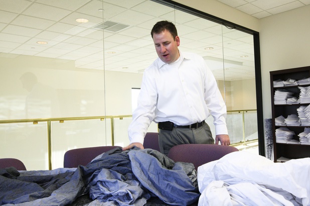 Executive Vice President Marty Martin explains how an ink-stained sheet was ruined by an anonymous perpetrator secretly sewing an ink packet in a white sheet during a walk-through of Apex Linen in Las Vegas Tuesday, October 30, 2013.