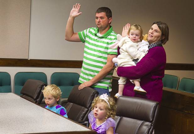 Terry Green and his wife Bethany Overland are sworn in as they adopt Sydney, 2, (dressed as a bunny) during a Halloween adoption day at Family Court Thursday, Oct. 31, 2013. At the desk are Skyler, 3, and Sasha, 4, Green.