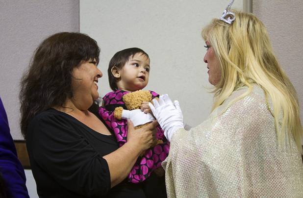 Judge Cynthia Giuliani, dressed as a fairy godmother, visits with Jasmine, 15 months, after she was formally adopted by Raquel Mendoza during a Halloween adoption day at Family Court Thursday, Oct. 31, 2013.
