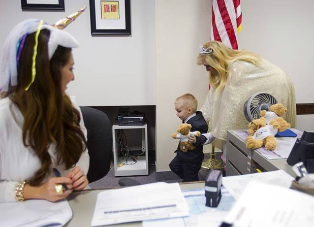 Gerardo Torres, 2, heads back to his family after receiving a teddy bear from Judge Cynthia Giuliani, dressed as a fairy godmother, during a Halloween adoption day at Family Court Thursday, Oct. 31, 2013.  Court clerk Nilly Tavares looks on at left.