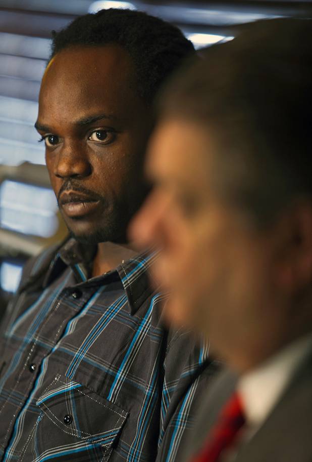 Antoine Hodges, left, looks to his lawyer Cal Potter as they talk about the filing of a federal lawsuit against the Metro Police department during a news conference at Potter's office Friday, Nov. 1, 2013. Hodges was mistaken as homicide suspect and shot by a Metro Police officer Oct. 21, 2013.
