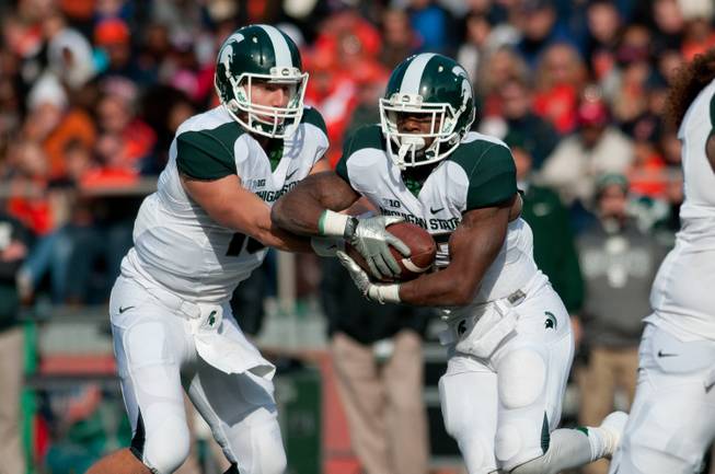 Michigan State quarterback Connor Cook hands the ball off to running back Jeremy Langford against Illinois during the first quarter of a game at Memorial Stadium in Champaign, Ill., Oct. 26, 2013.