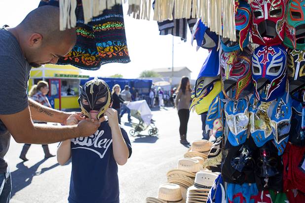 Anthony Alvarez, 9,  tries on a Mexican luchador (wrestling) mask with his father Miguel at the Broadacres Marketplace & Events Center Sunday Nov. 3, 2013.