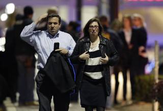 A man and woman leave the Garden State Plaza Mall with officials standing guard behind them following reports of a shooter, Monday, Nov. 4, 2013, in Paramus, N.J. Hundreds of law enforcement officers converged on the mall Monday night after witnesses said multiple shots were fired there.