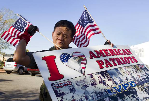 Sothy Seang, owner of the Donut Hut, puts flags in his sign before marching in the Veterans Day parade in downtown Las Vegas Monday, Nov. 11, 2013. Seang fought with the Cambodian army against the Viet Cong during the Vietnam War.