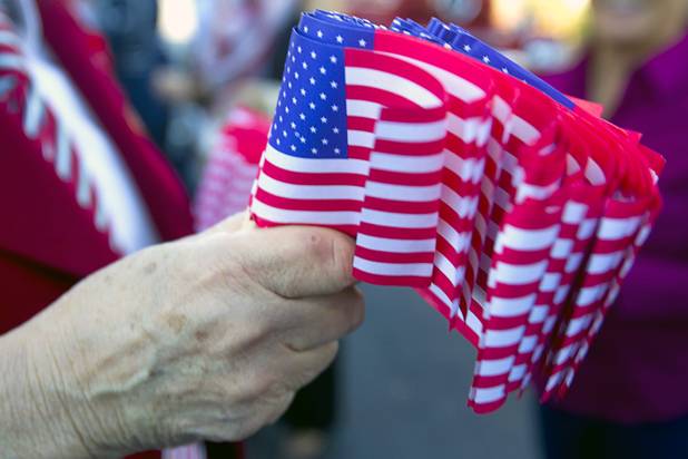 Las Vegas Mayor Carolyn Goodman holds American flags before the start of the annual Veterans Day parade in downtown Las Vegas Monday, Nov. 11, 2013.