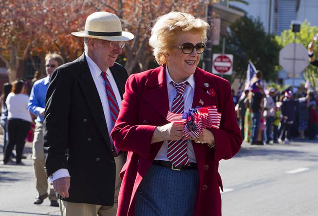 Former Mayor Oscar Goodman and his wife Mayor Carolyn Goodman hand out flags during the annual Veterans Day parade in downtown Las Vegas Monday, Nov. 11, 2013.