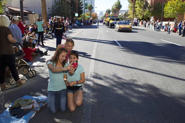 Girls take a self-portrait on their phone during the annual Veterans Day parade in downtown Las Vegas Monday, Nov. 11, 2013.