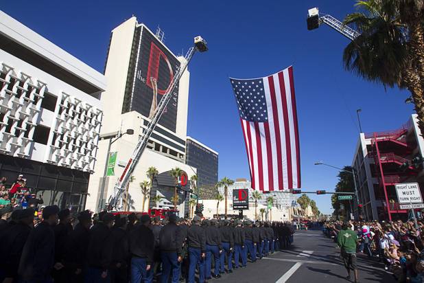 Parade participants pass under an American flag during the annual Veterans Day parade in downtown Las Vegas Monday, Nov. 11, 2013.