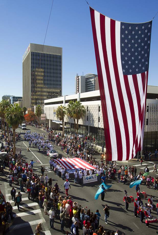 Parade participants pass under an American flag during the annual Veterans Day parade in downtown Las Vegas Monday, Nov. 11, 2013.