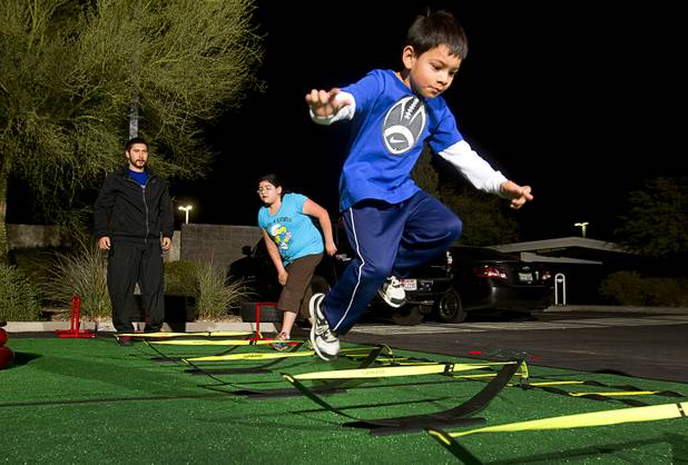 Steve Naparty, director of children programs, watches as Ana Rodriguez, 11, and her brother Andrew, 4, run through a course during a Kids Fitness class at the Colosseum Training Center, in the Cashman Equipment complex on St. Rose Parkway, Thursday, Nov. 14, 2013.